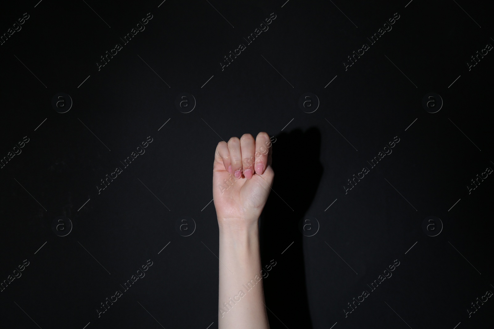 Photo of SOS gesture. Woman showing signal for help on black background, closeup