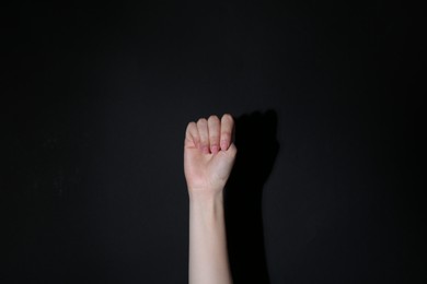 Photo of SOS gesture. Woman showing signal for help on black background, closeup