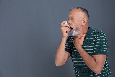 Photo of Man using asthma inhaler on color background with space for text