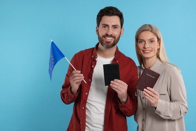 Immigration. Happy couple with passports and flag of European Union on light blue background