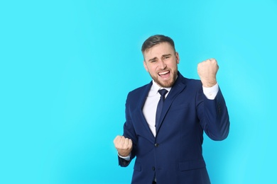 Photo of Portrait of emotional young businessman on color background. Space for text