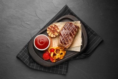 Photo of Delicious grilled beef steak with spices and tomato sauce on dark gray table, top view