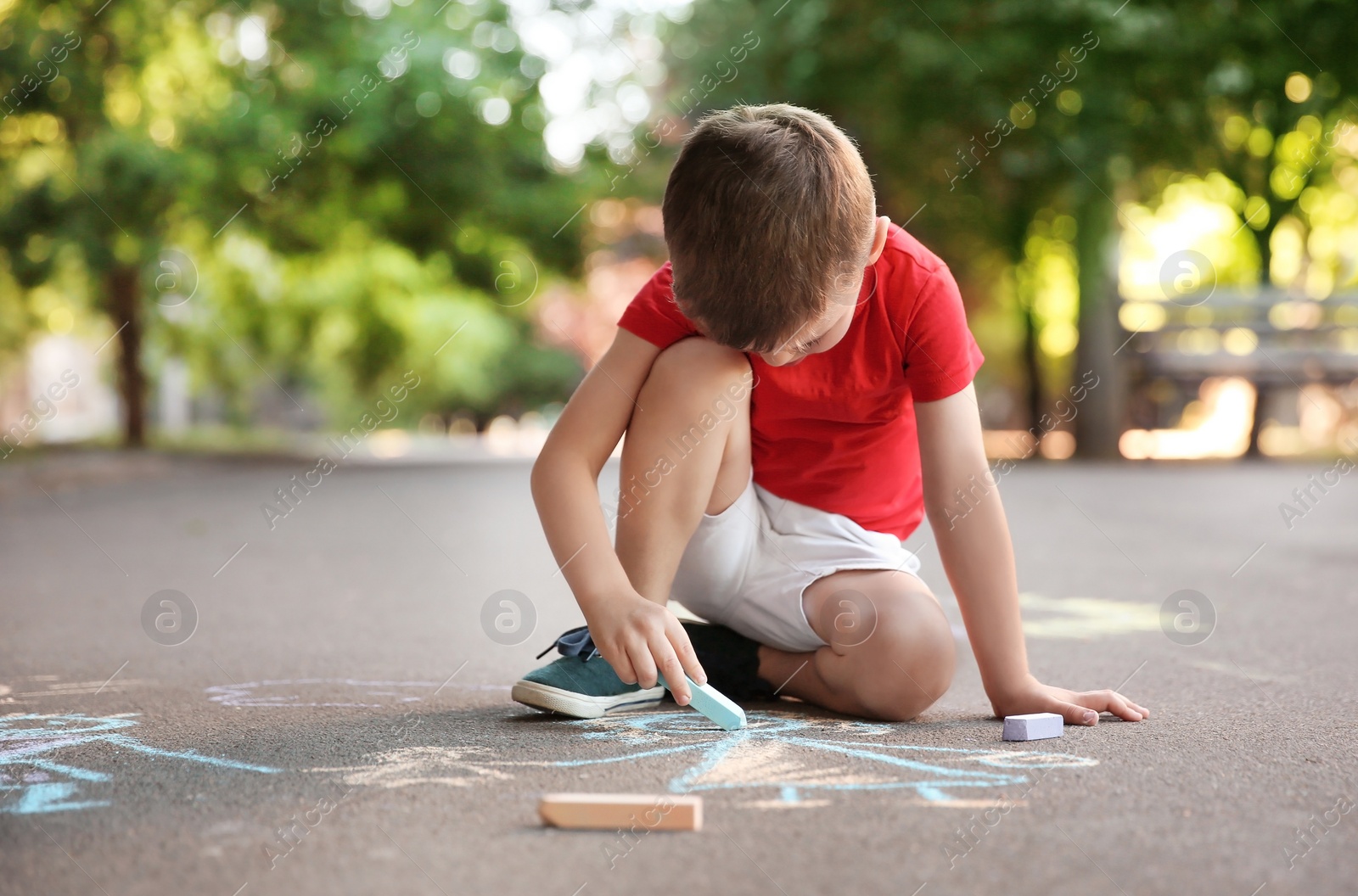 Photo of Little child drawing family with chalk on asphalt