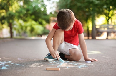 Little child drawing family with chalk on asphalt