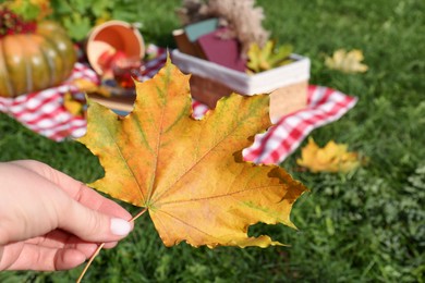 Woman holding yellow maple leaf outdoors, closeup. Autumn season