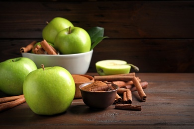 Photo of Fresh apples with cinnamon sticks and powder on wooden table