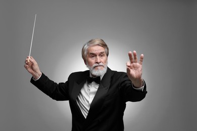 Photo of Professional conductor with baton on grey background