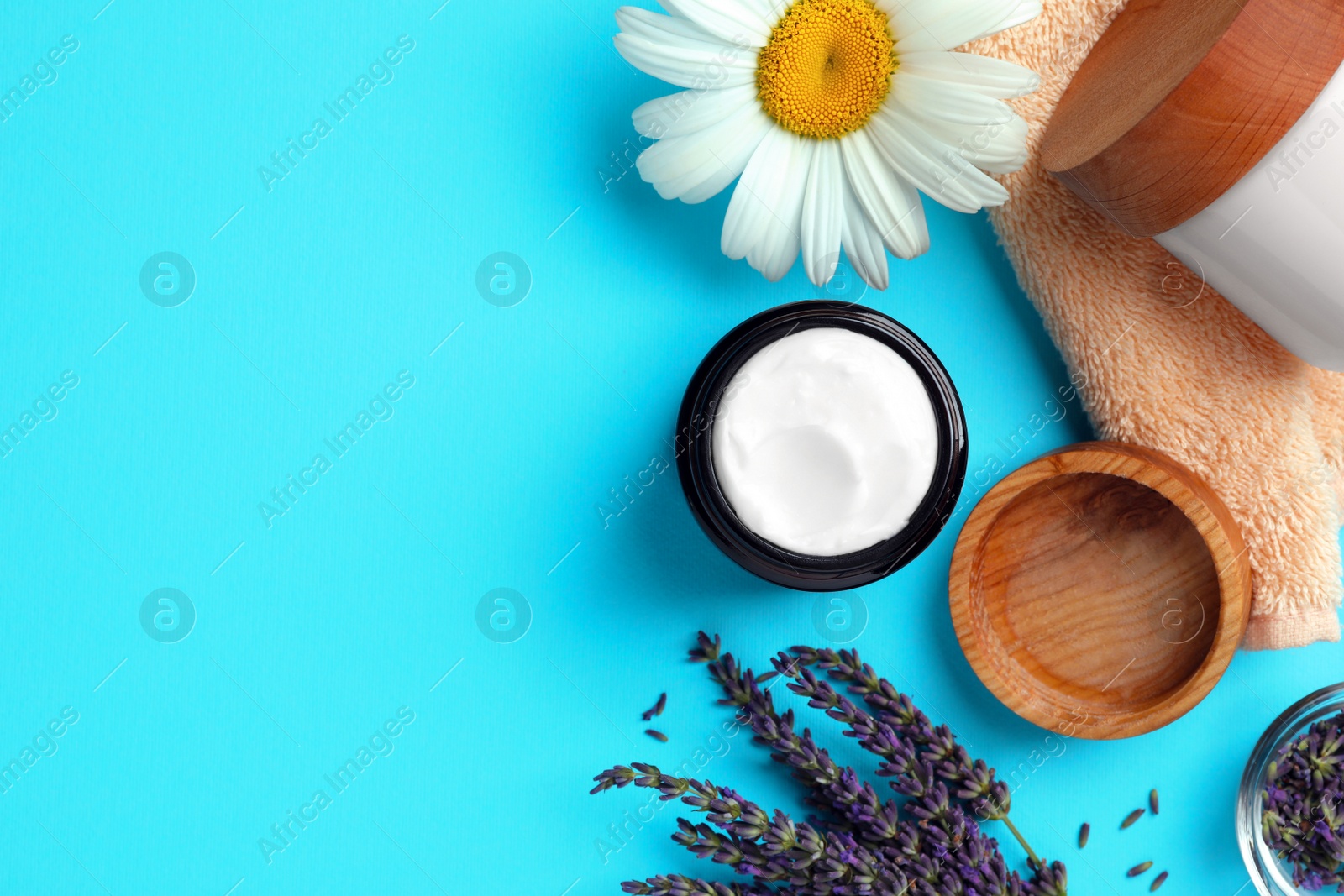 Photo of Flat lay composition with jar of face cream and beautiful flowers on light blue background. Space for text