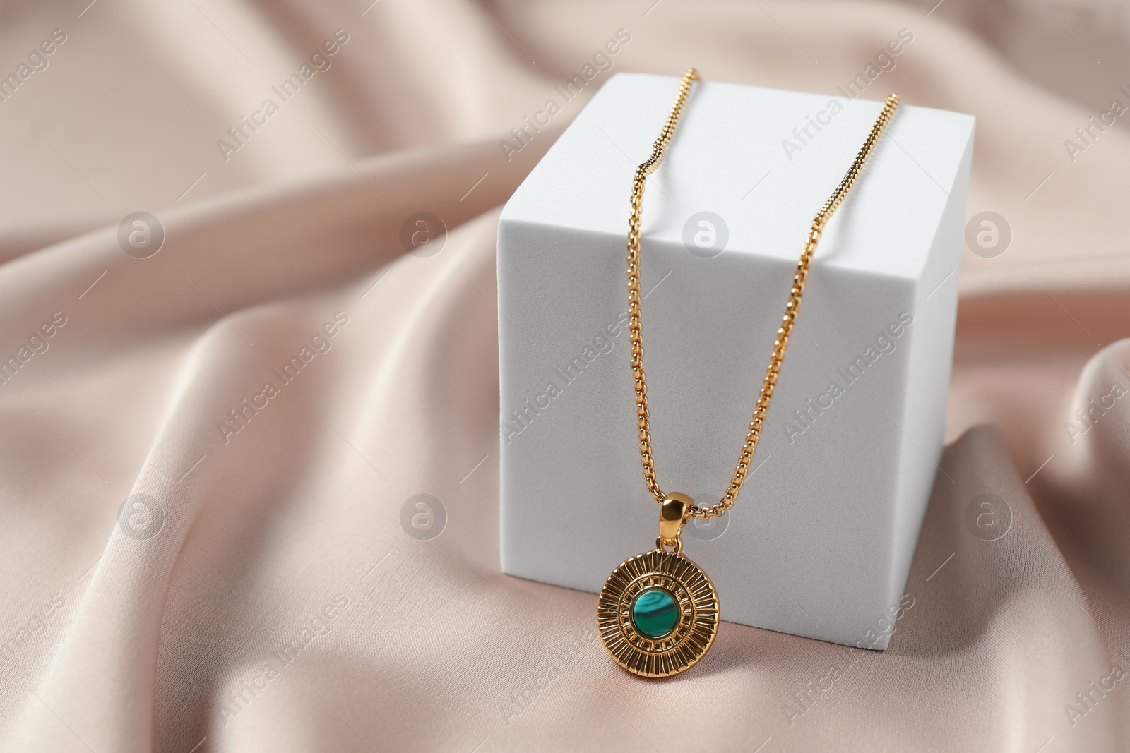 Photo of Stylish presentation of elegant necklace on beige cloth, space for text