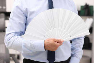 Businessman with white hand fan in office, closeup