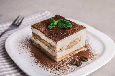 Photo of Plate of tiramisu cake on grey table, closeup