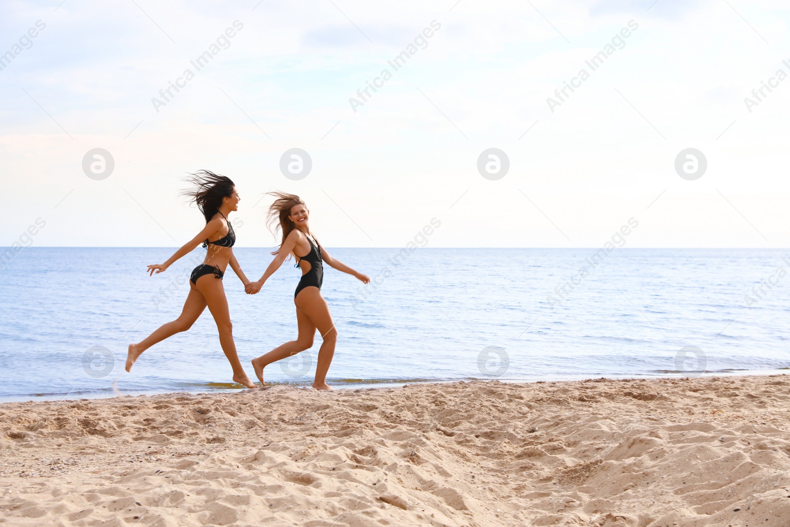 Photo of Young woman in bikini with girlfriend on beach. Lovely couple