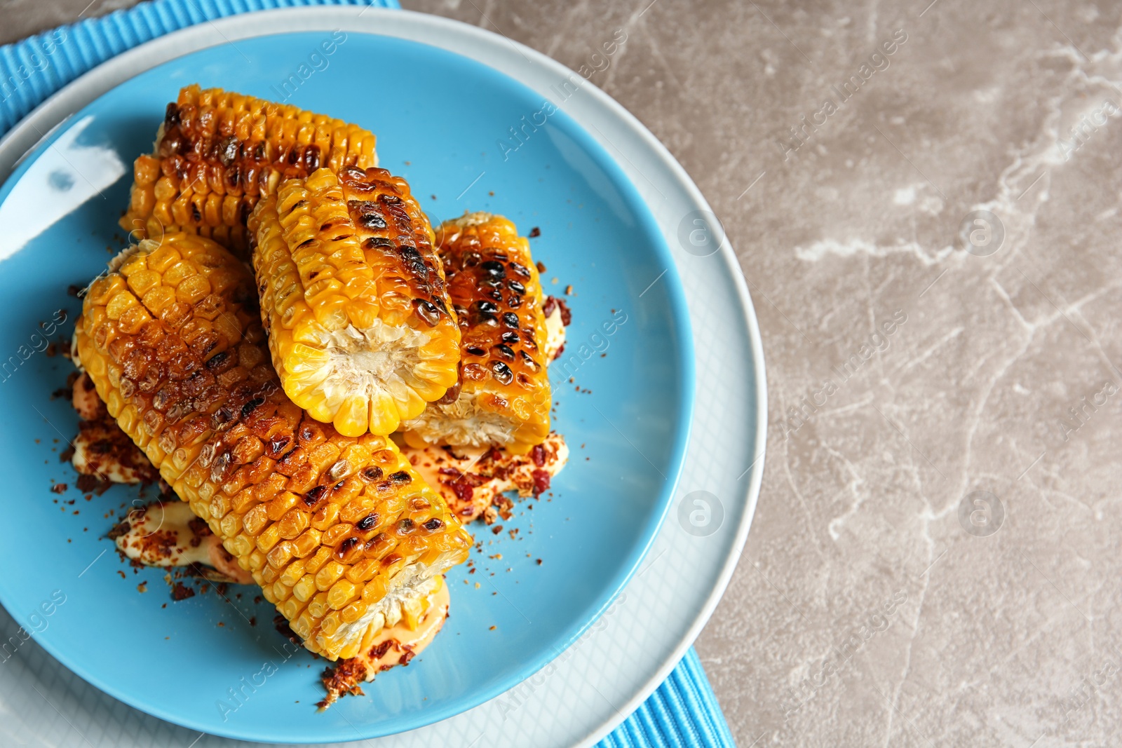 Photo of Plate with delicious grilled corn cobs and spices on table, top view. Space for text