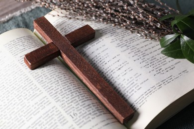 Bible, wooden cross and bouquet with willow branches on table, closeup