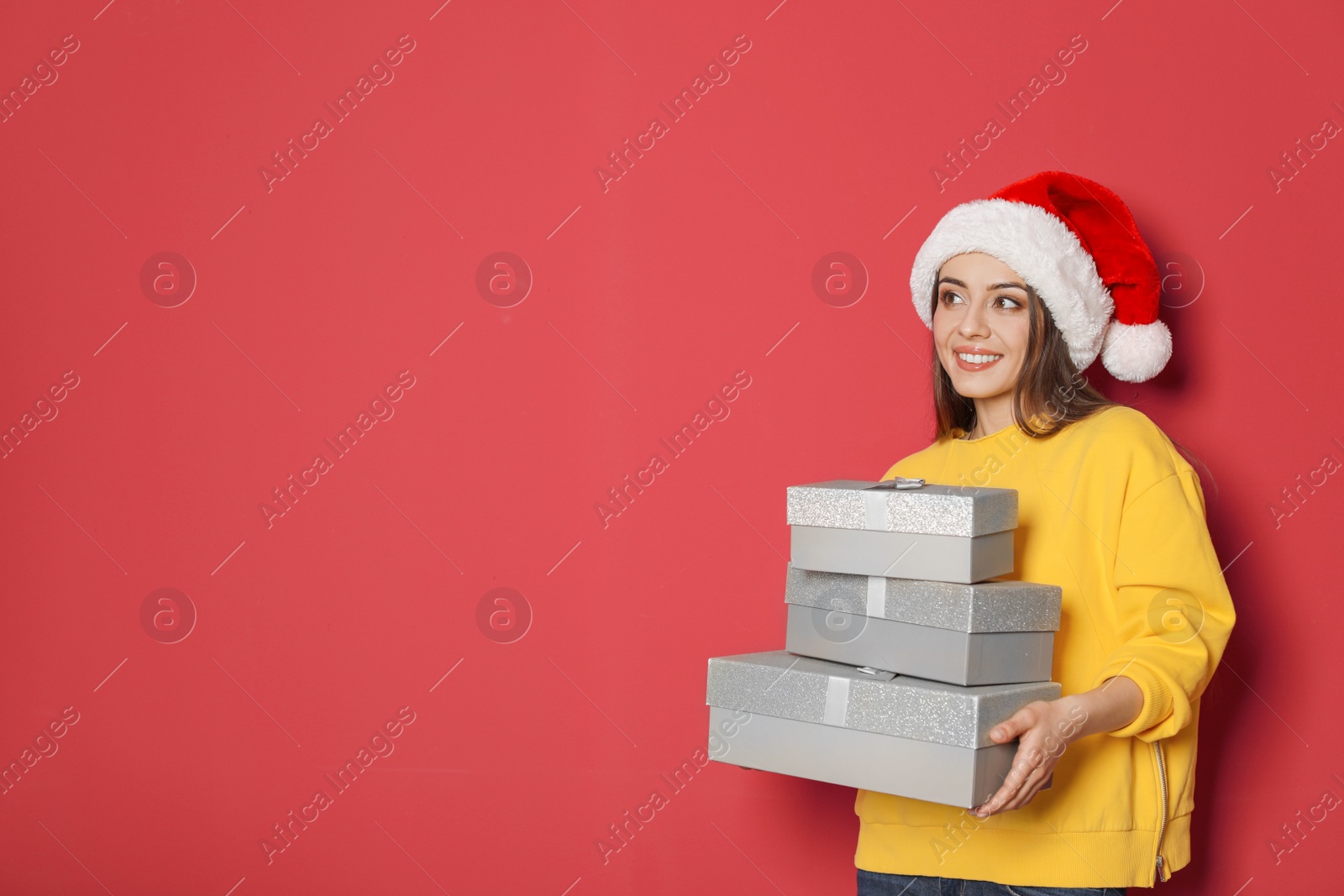 Photo of Young woman with Christmas gifts on color background