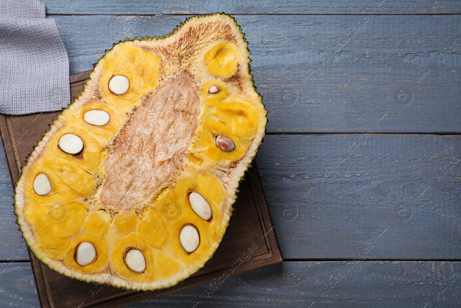 Photo of Delicious exotic jackfruit on grey wooden table, top view. Space for text