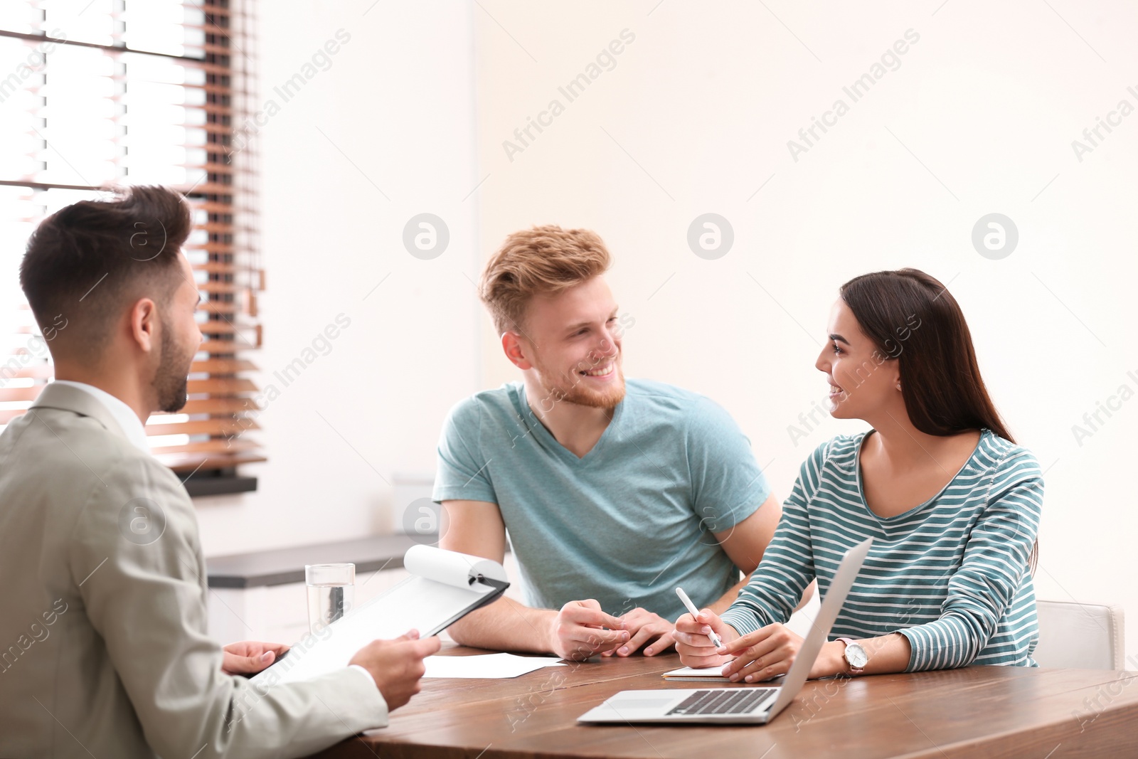 Photo of Insurance agent consulting young couple in office