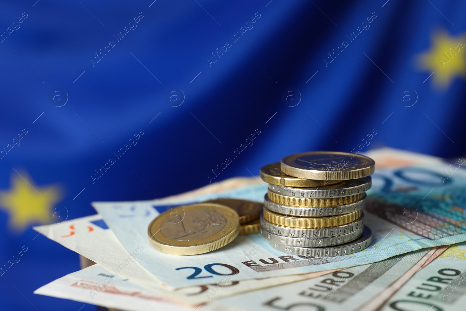 Photo of Coins and banknotes against European Union flag, closeup. Space for text