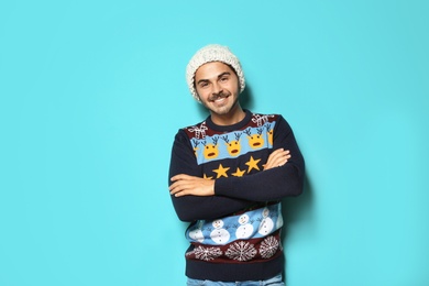 Photo of Young man in Christmas sweater and knitted hat on color background