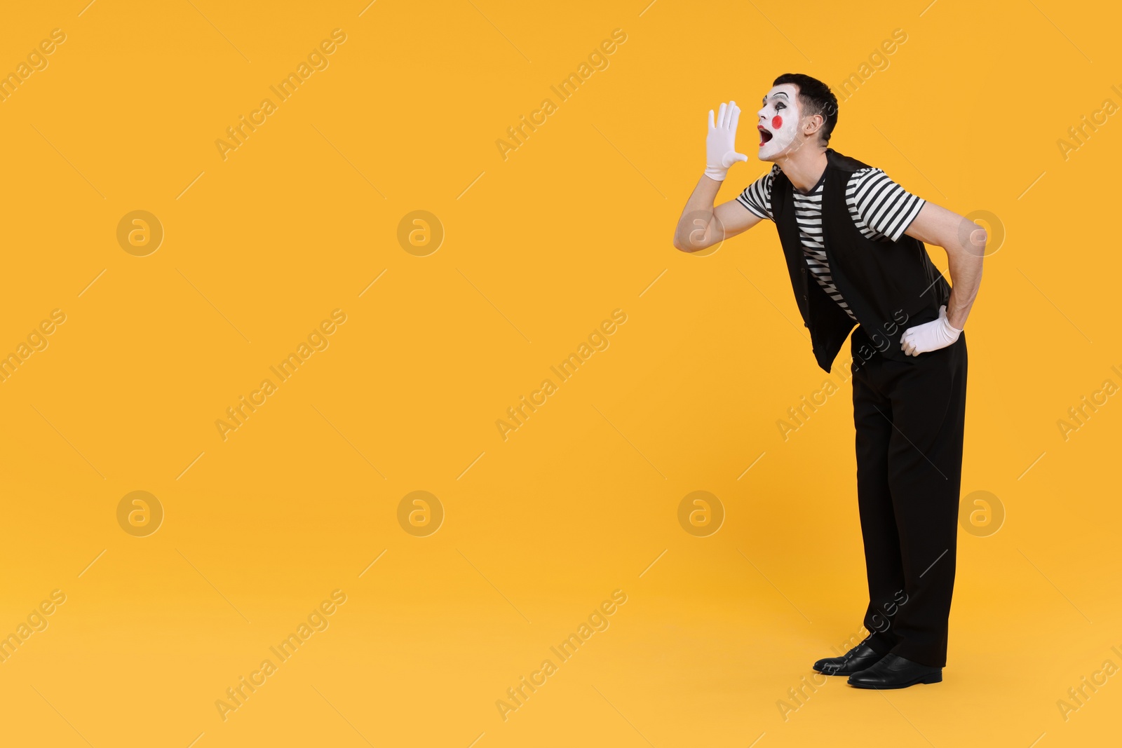 Photo of Funny mime artist screaming on orange background. Space for text