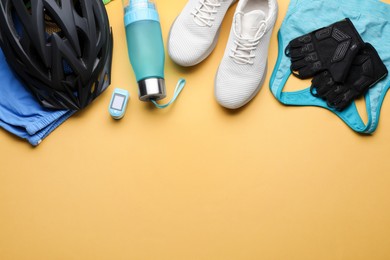 Photo of Flat lay composition with different cycling accessories and clothes on pale orange background, space for text