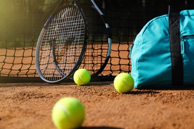 Photo of Tennis balls, rackets and bag near net on clay court