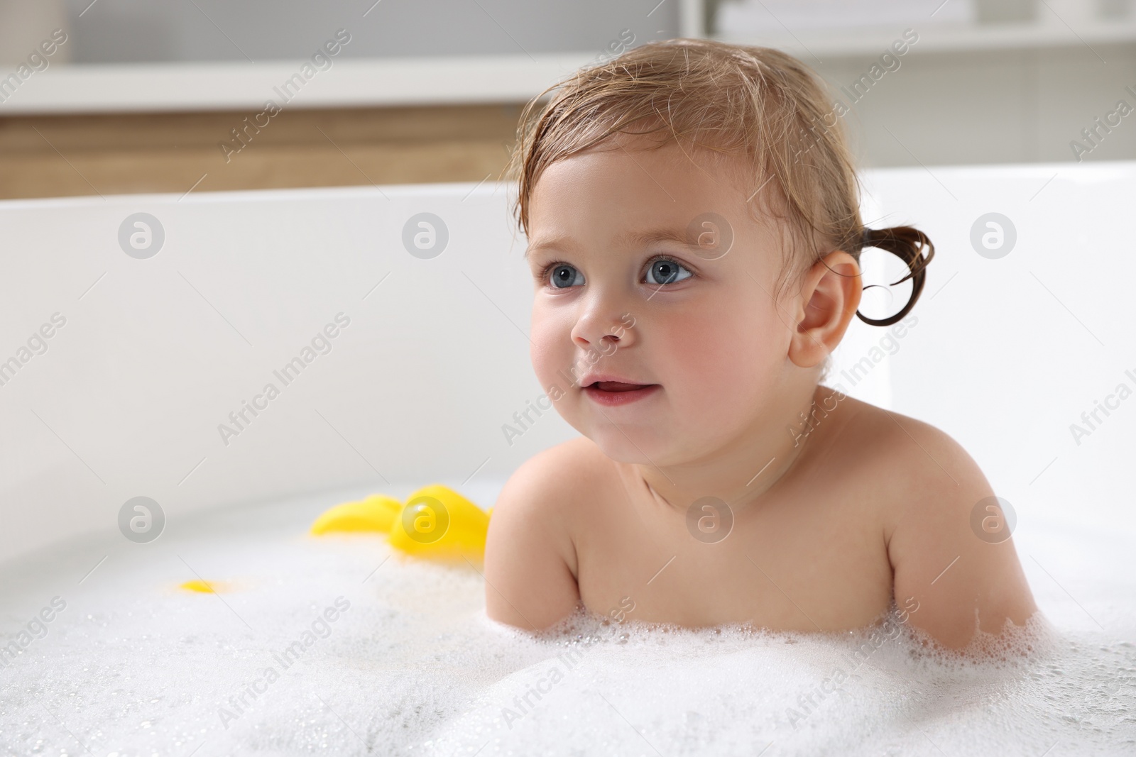 Photo of Cute little girl taking foamy bath at home