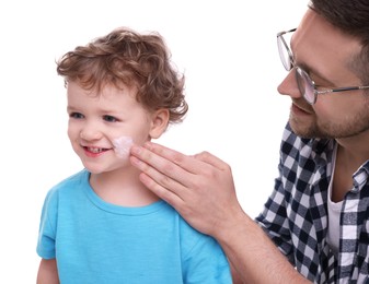 Photo of Father applying ointment onto his son`s cheek on white background