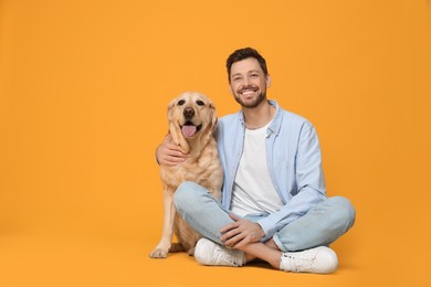 Photo of Happy man with his cute Labrador Retriever on yellow background. Space for text