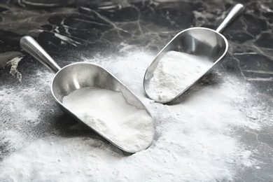 Scoops and baking soda on grey background