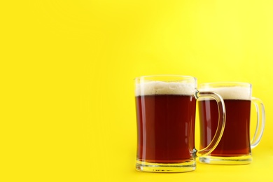 Photo of Delicious homemade kvass in glass mugs on yellow background. Space for text