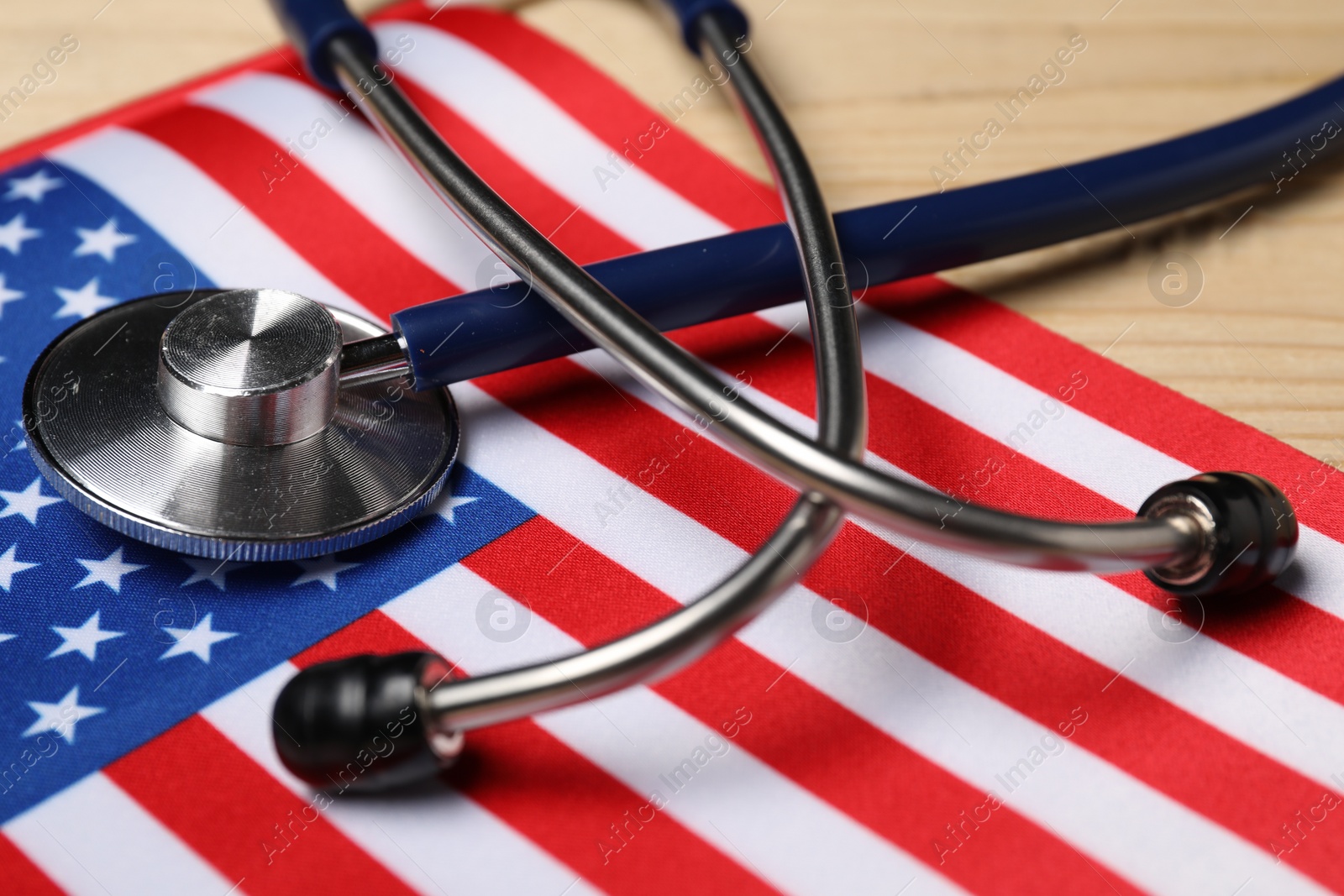 Photo of Stethoscope and USA flag on wooden table, closeup. Health care concept