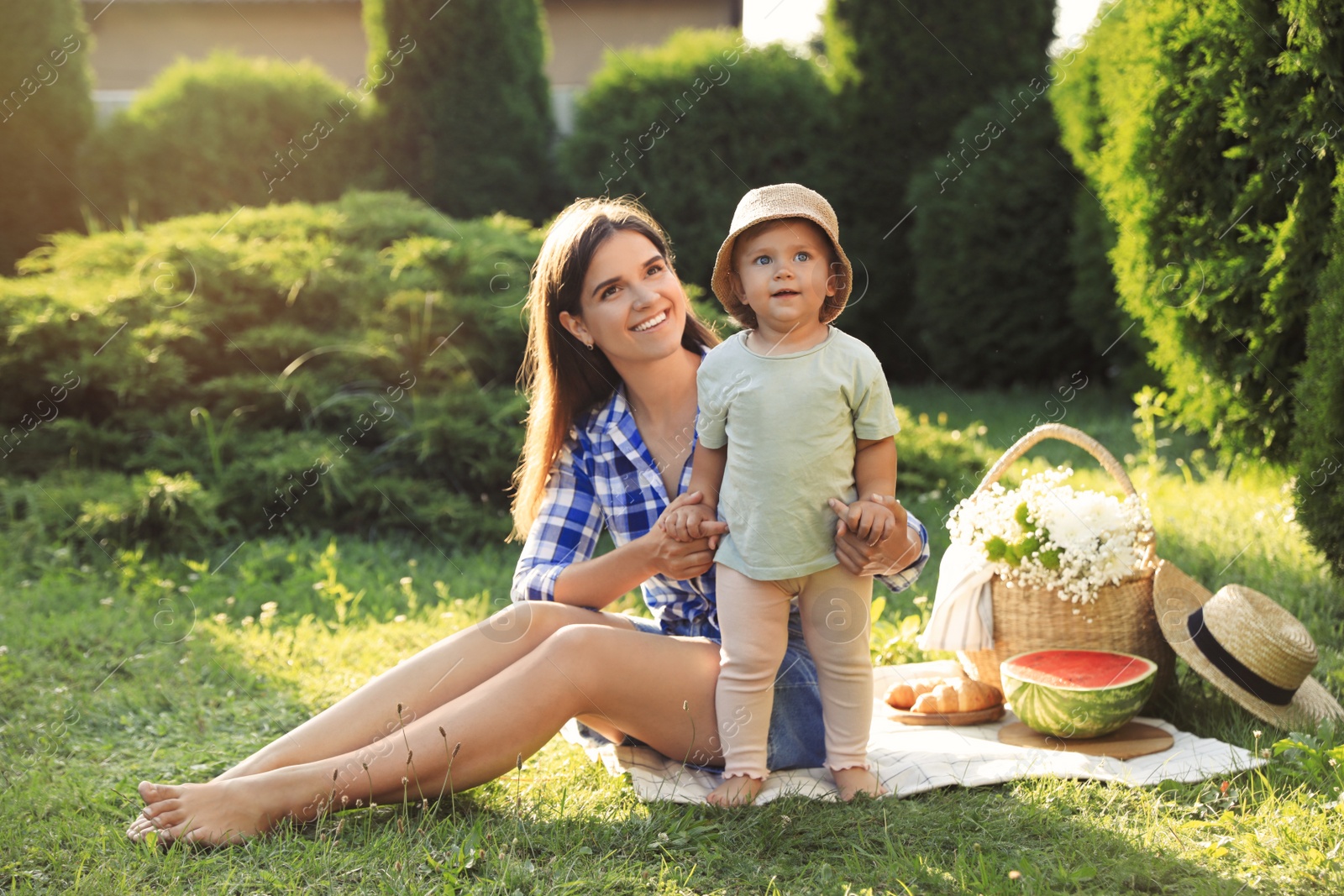 Photo of Mother with her baby daughter having picnic in garden on sunny day