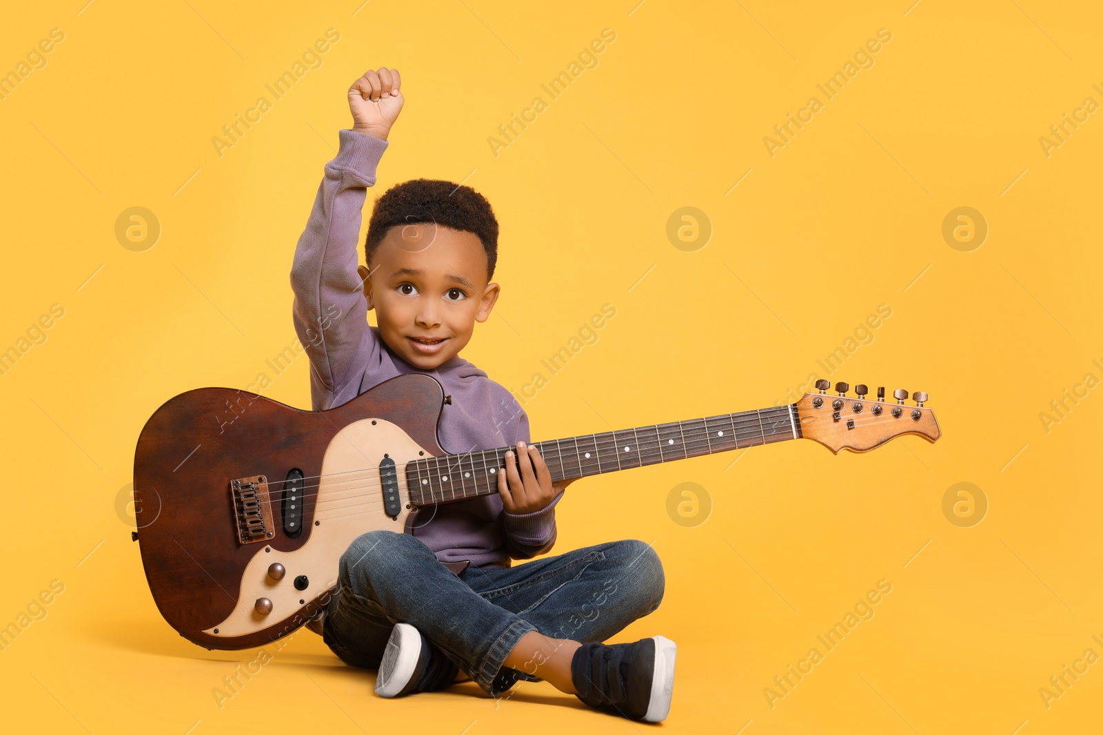 Photo of African-American boy with electric guitar on yellow background. Space for text