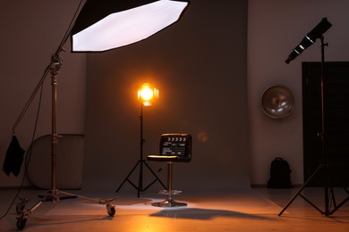 Photo of Casting call. Chair, clapperboard and different equipment in modern studio