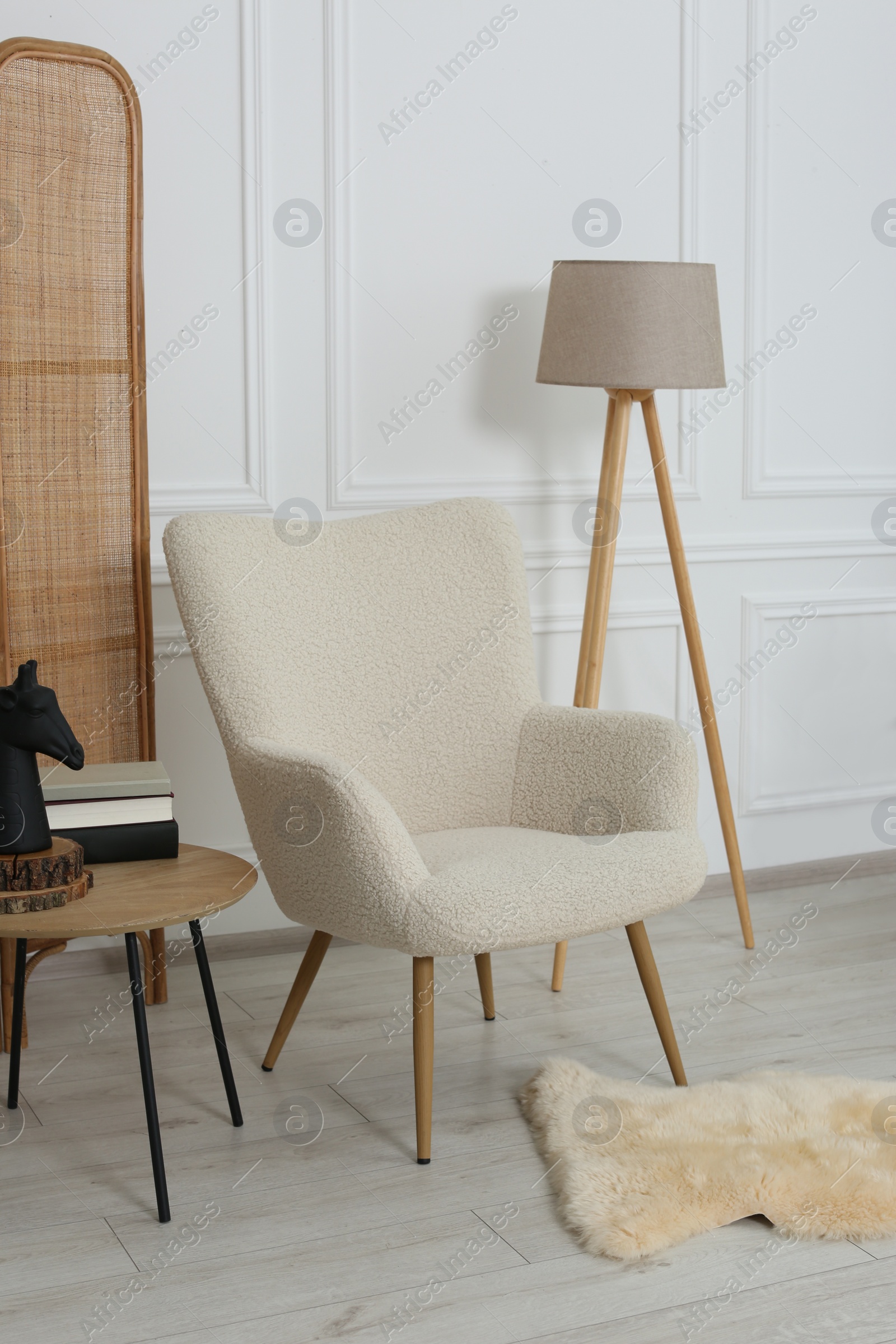 Photo of Stylish beige armchair and small coffee table in living room. Interior design