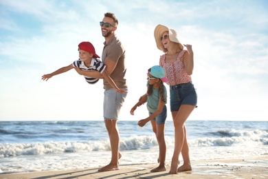 Photo of Happy family having fun on sandy beach near sea