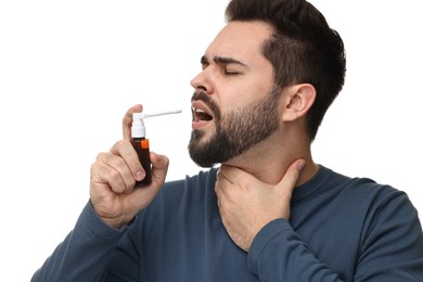 Young man using throat spray on white background