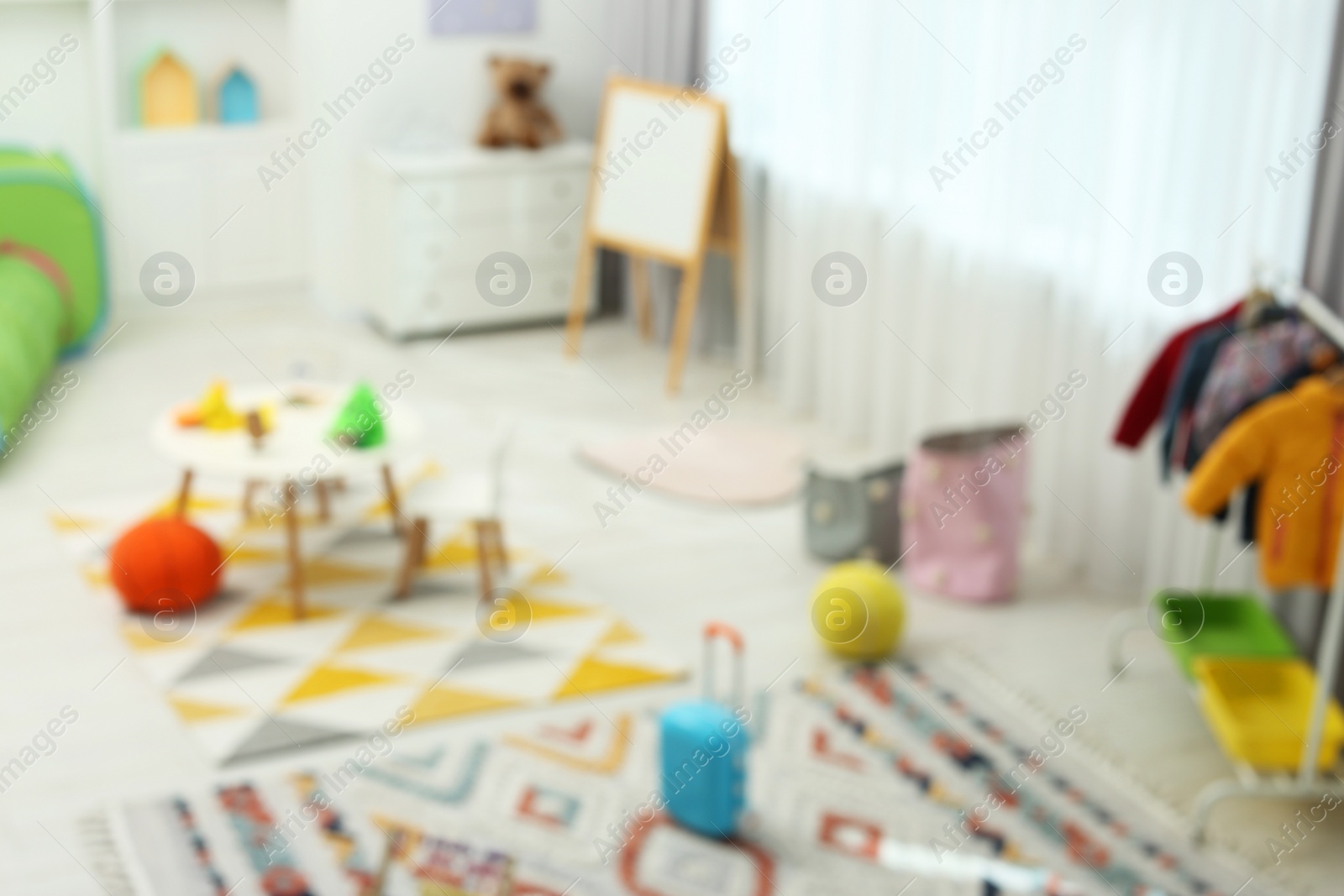 Photo of Blurred view of child`s playroom with different toys and furniture. Stylish kindergarten interior