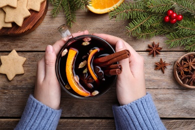 Photo of Woman with cup of mulled wine at wooden table, top view