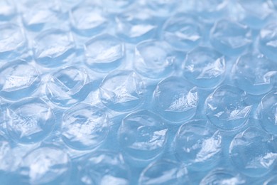 Photo of Transparent bubble wrap on light blue background, closeup