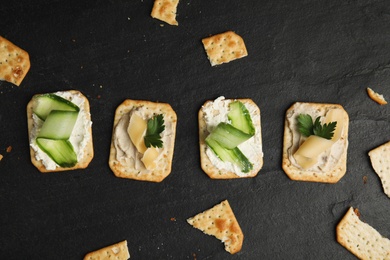 Photo of Delicious crackers with humus and cheese on black table, flat lay