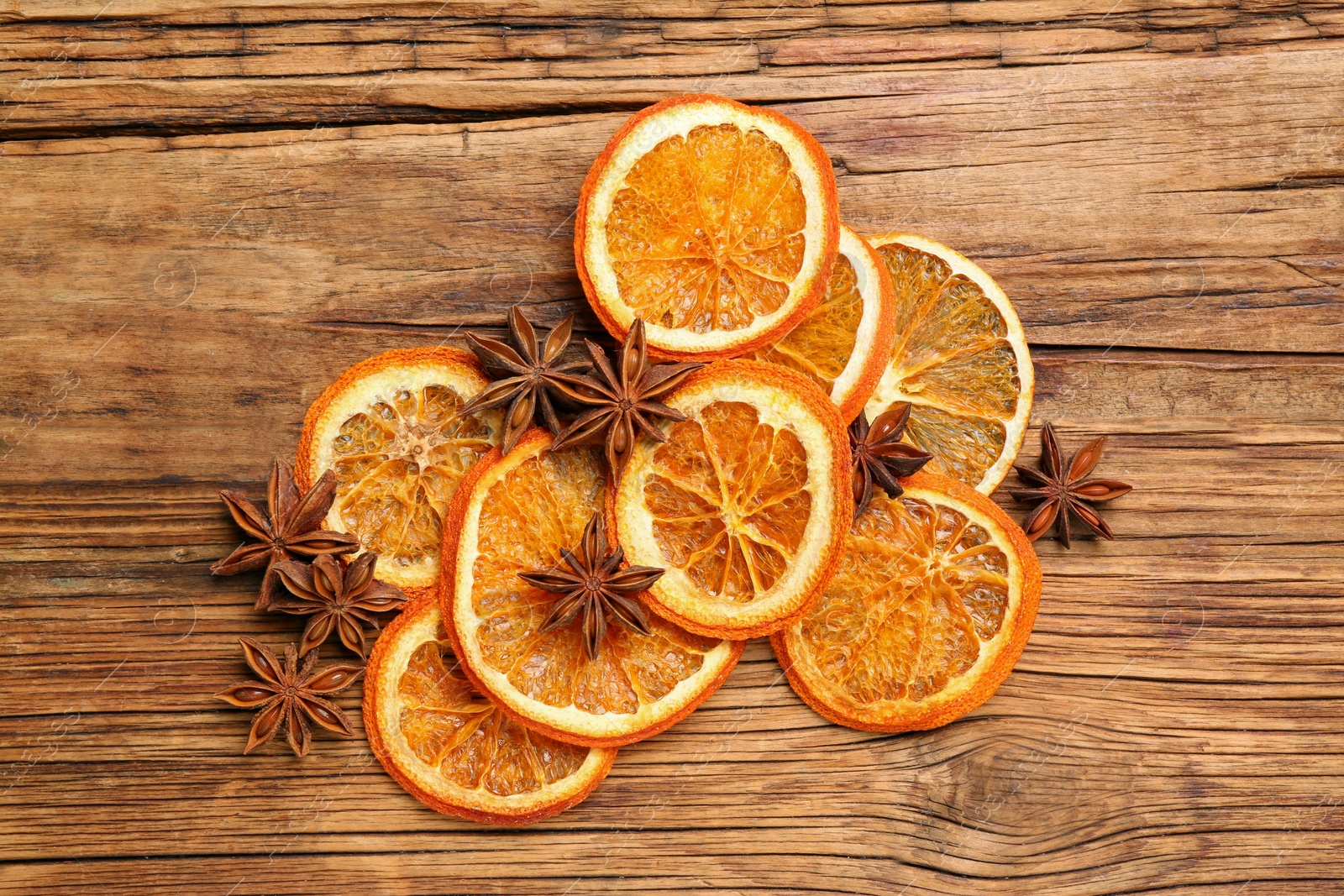 Photo of Dry orange slices and anise stars on wooden table, flat lay