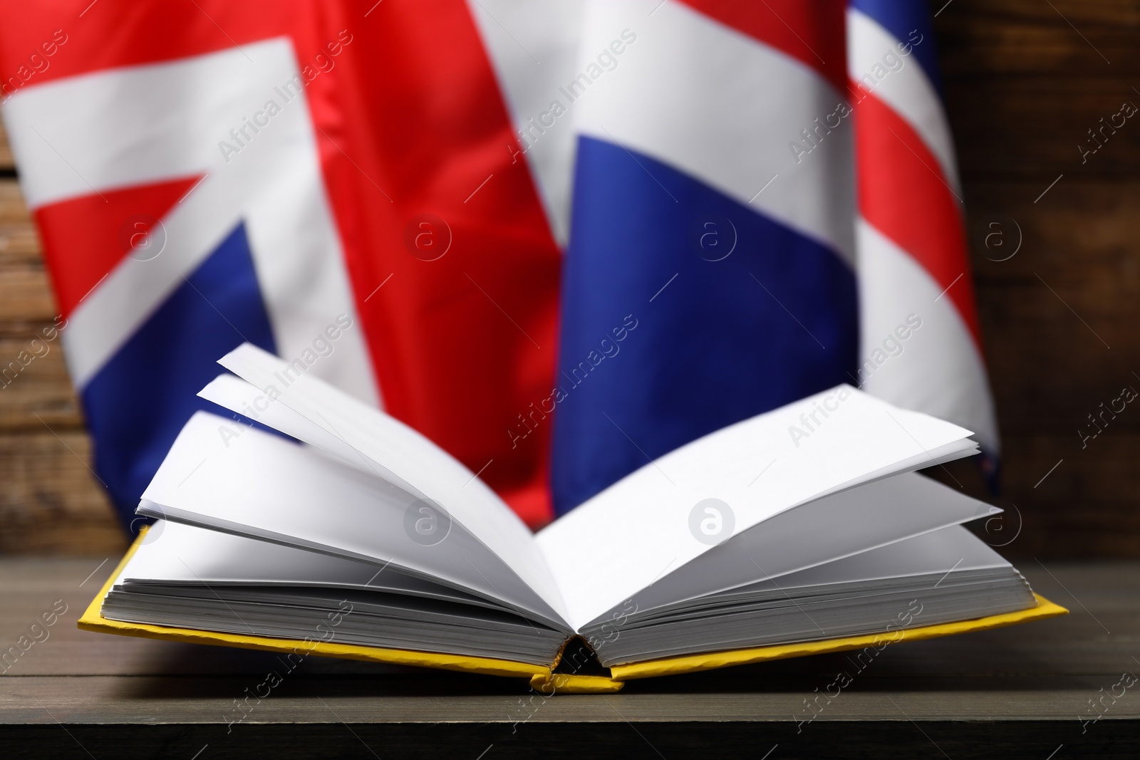 Photo of Learning foreign language. Open book on wooden table flag of United Kingdom, space for text