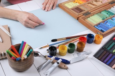 Photo of Artist drawing with chalk pastel at white wooden table, closeup