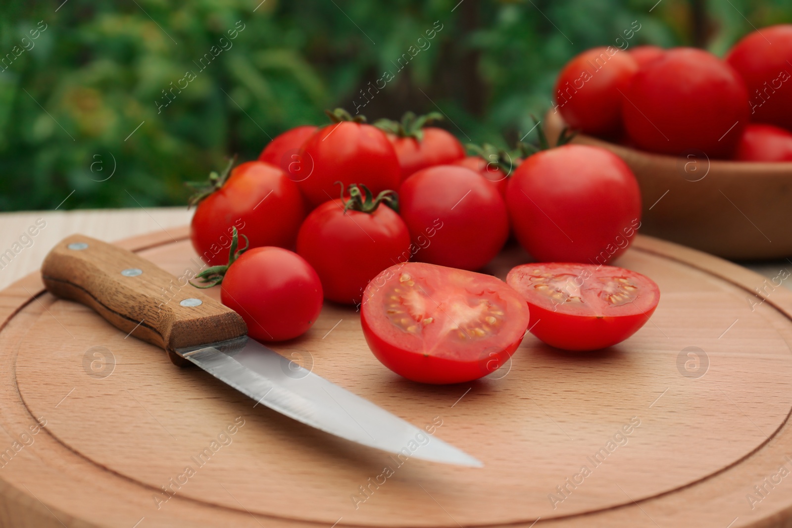 Photo of Cut and whole ripe red tomatoes with knife on table in garden