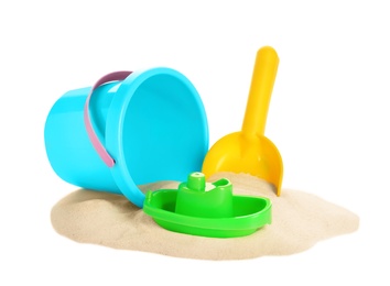 Plastic beach toys on pile of sand against white background