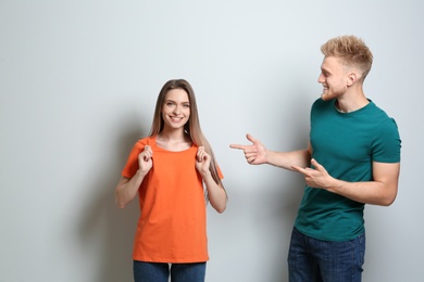 Photo of Young couple wearing blank t-shirts on light background. Mockup for design