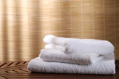 Photo of Stacked soft towels on wooden table indoors