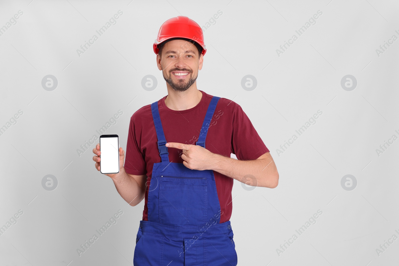 Photo of Professional repairman in uniform with phone on white background